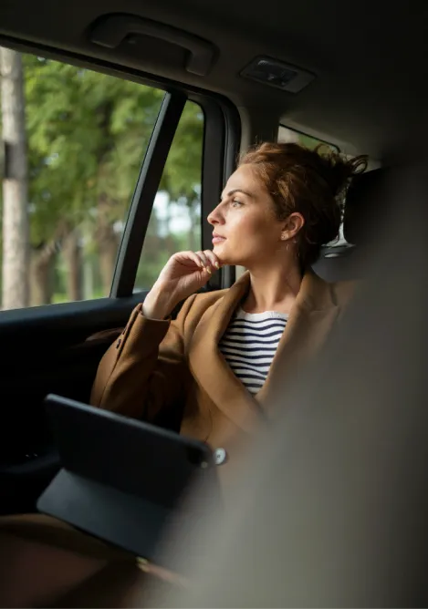 Une femme dans un vtc qui regarde dehors en profitant de son trajet