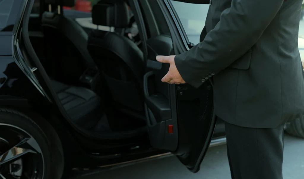 Un chauffeur Ride'Art en costume ouvrant la porte du véhicule pour son client